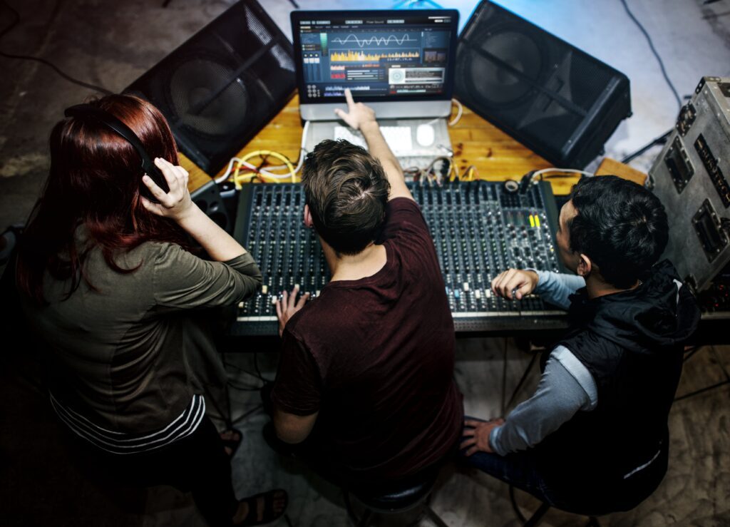 Drie professionals aan professioneel mengpaneel tijdens sound design sessie voor podcast